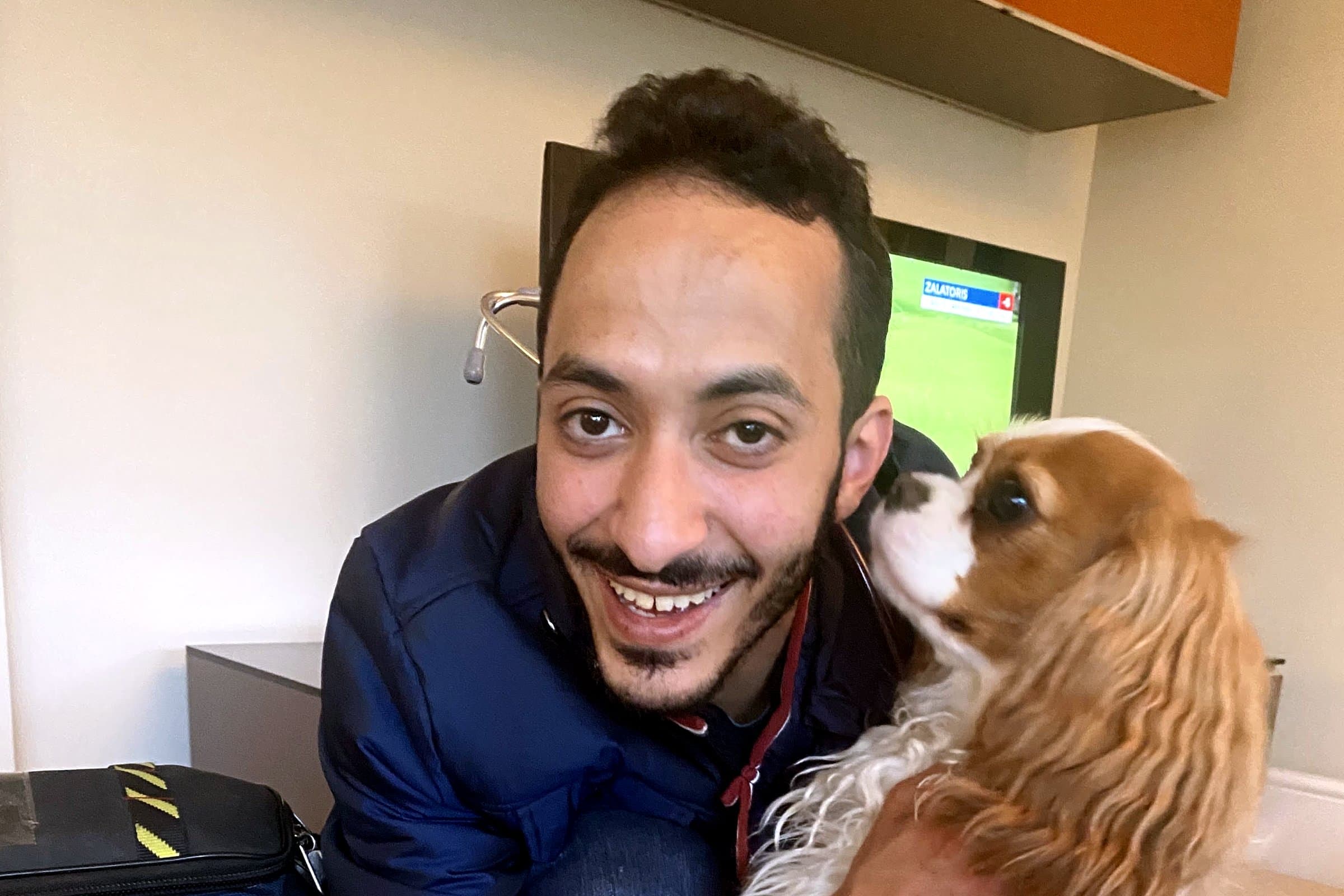Ziad kneeling beside his diagnostic and surgical bags, holding a cavalier king charles spaniel during a home visit